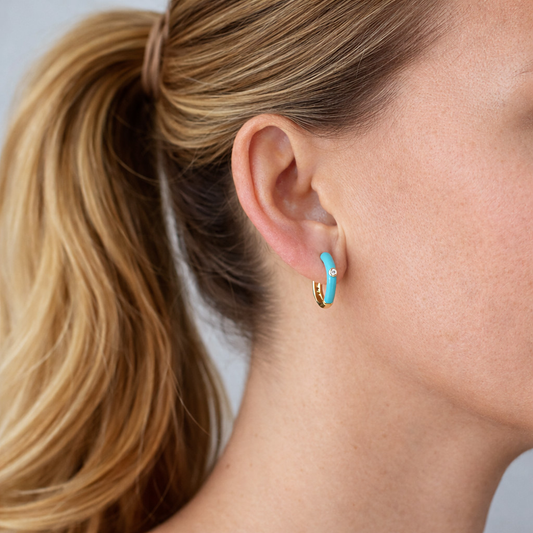 Pendientes Silvia puestos en la oreja, aros pequeños bañados en oro con esmalte azul