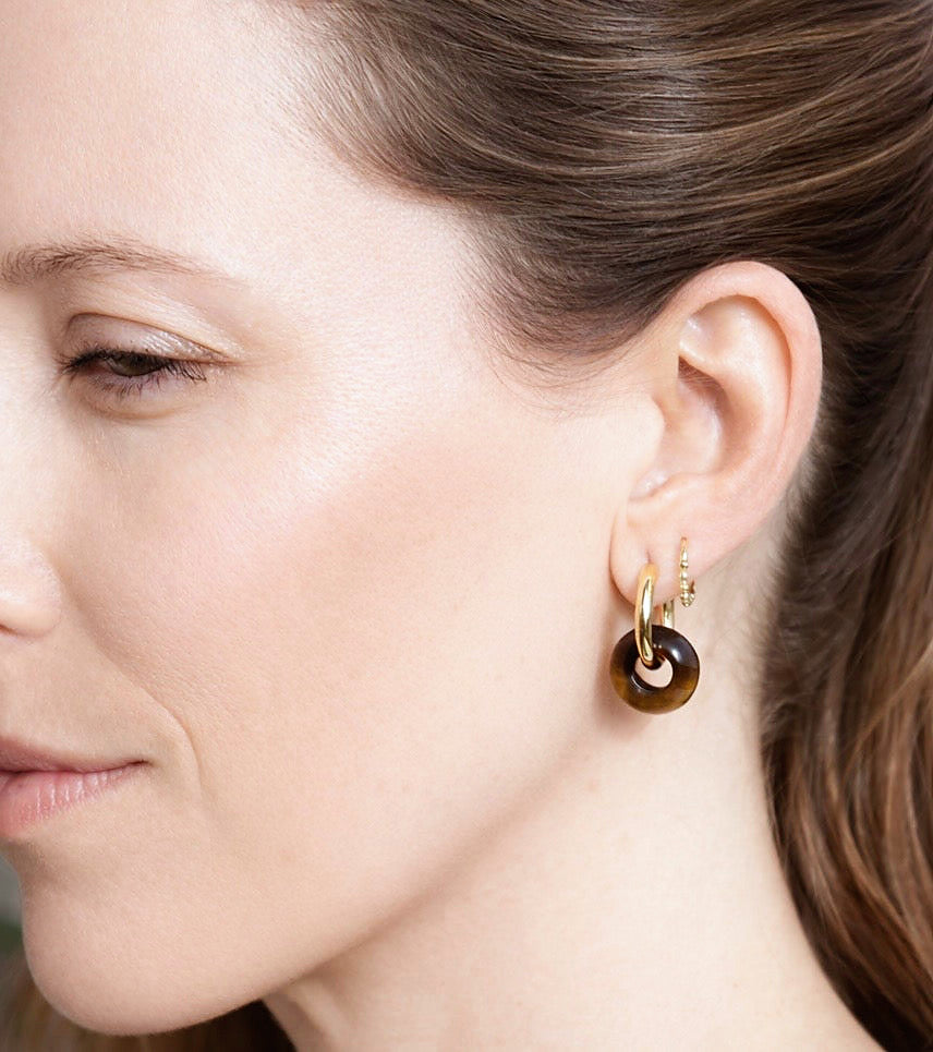 Pendientes Pia puestos en la oreja, aros dorados con colgante de piedra natural marrón