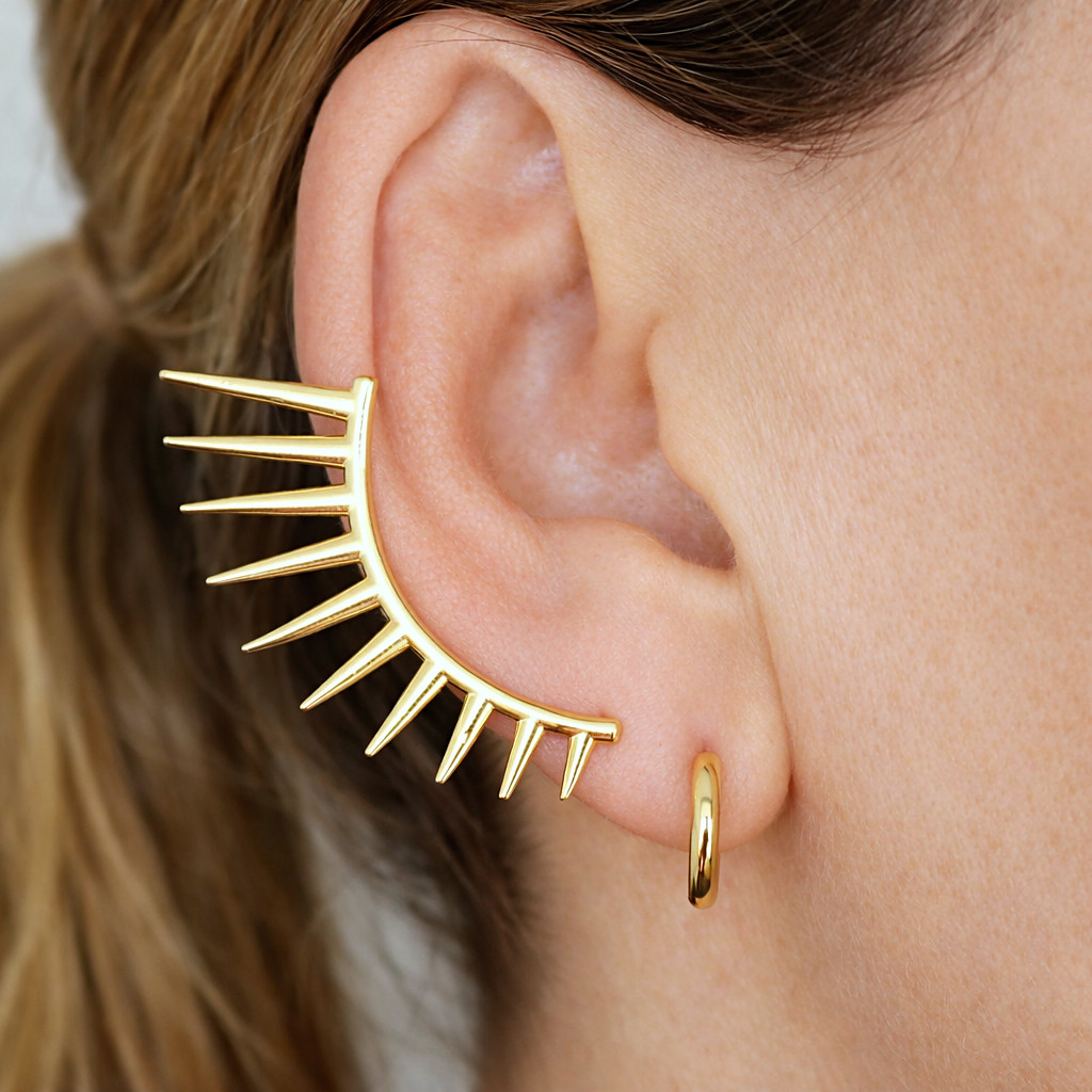 Ear cuff dorado con puntas y aro pequeño dorado puestos en la misma oreja, vista de perfil