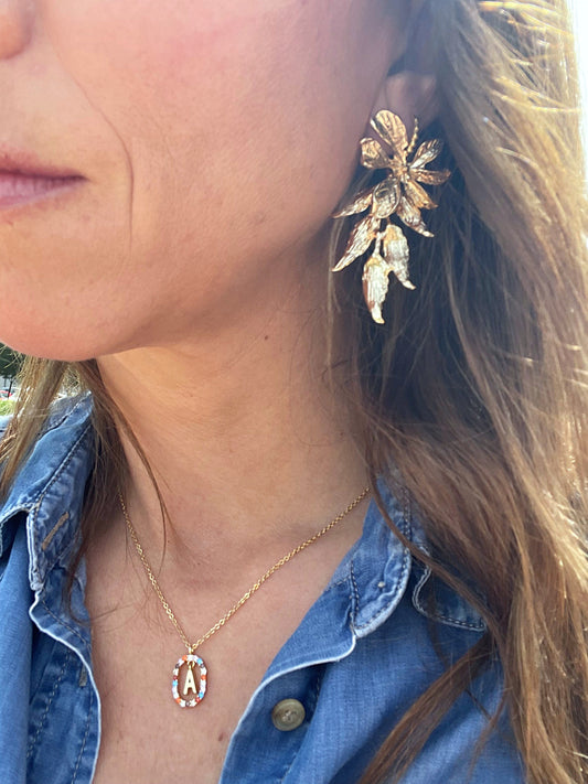 Pendientes Ana puestos en la oreja, pendientes largos de diseño floral bañados en oro