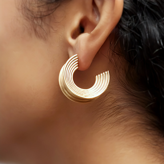 Pendientes Aura puestos en la oreja, aros en forma de abanico bañados en oro de 18 quilates