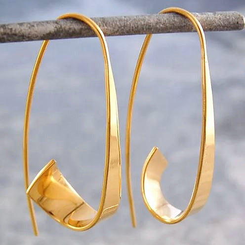 Pendientes Eugenia, aros dorados en espiral colgados de una rama, vista de cerca