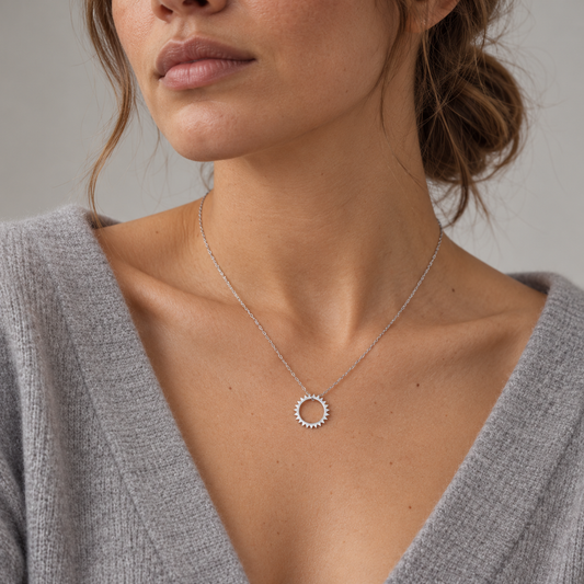 Collar fino de plata de ley 925 con colgante de sol calado puesto con jersey gris de pico