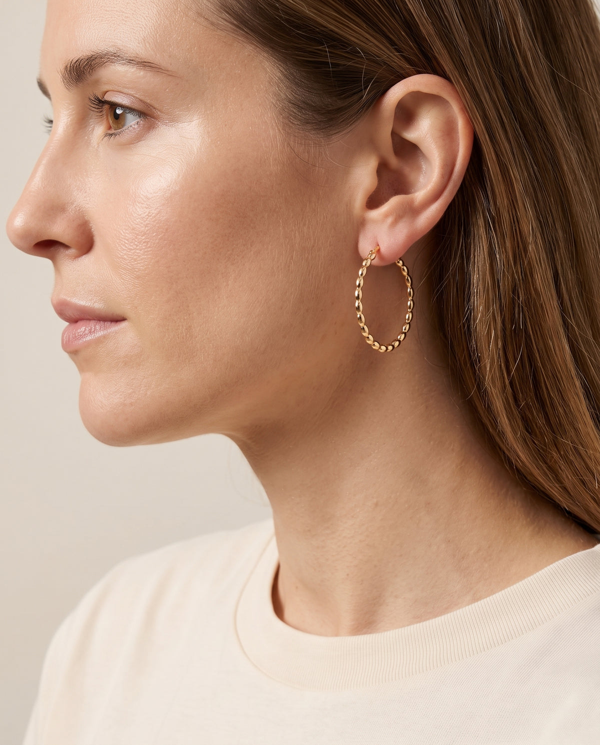 Pendientes Elvira, aro dorado texturizado, puesto en la oreja con el pelo recogido